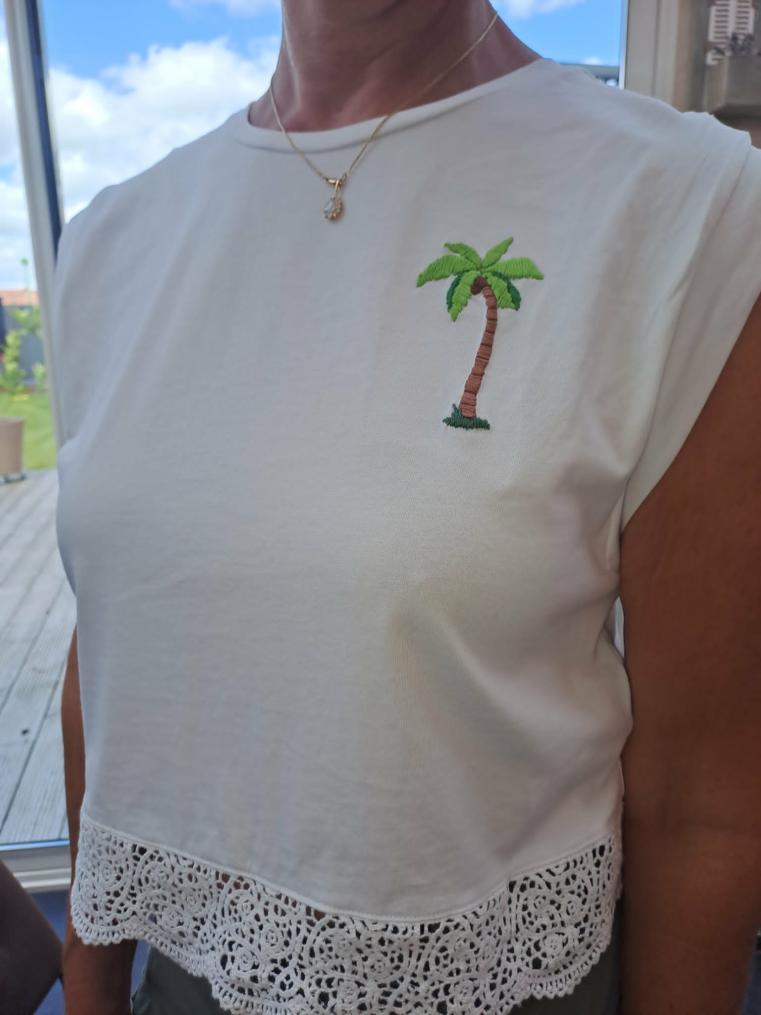 broderie à la main d'un petit palmier sur la poitrine d'un tee-shirt blanc