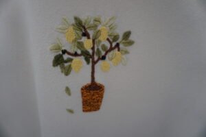 broderie à la main d'un citronnier en pot sur un sweat écru à plat