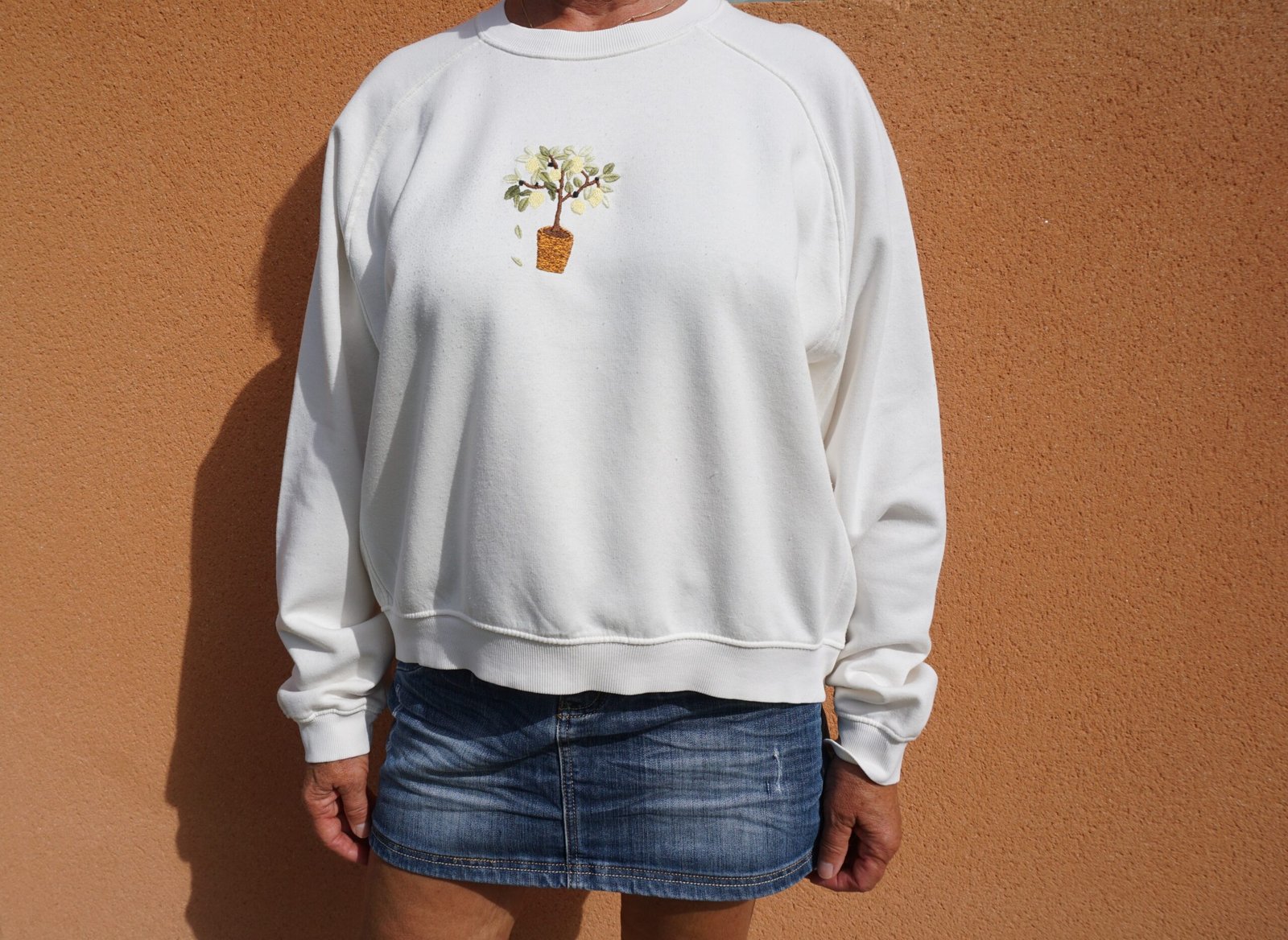 broderie à la main d'un citronnier en pot sur la poitrine d'un sweat écru porté