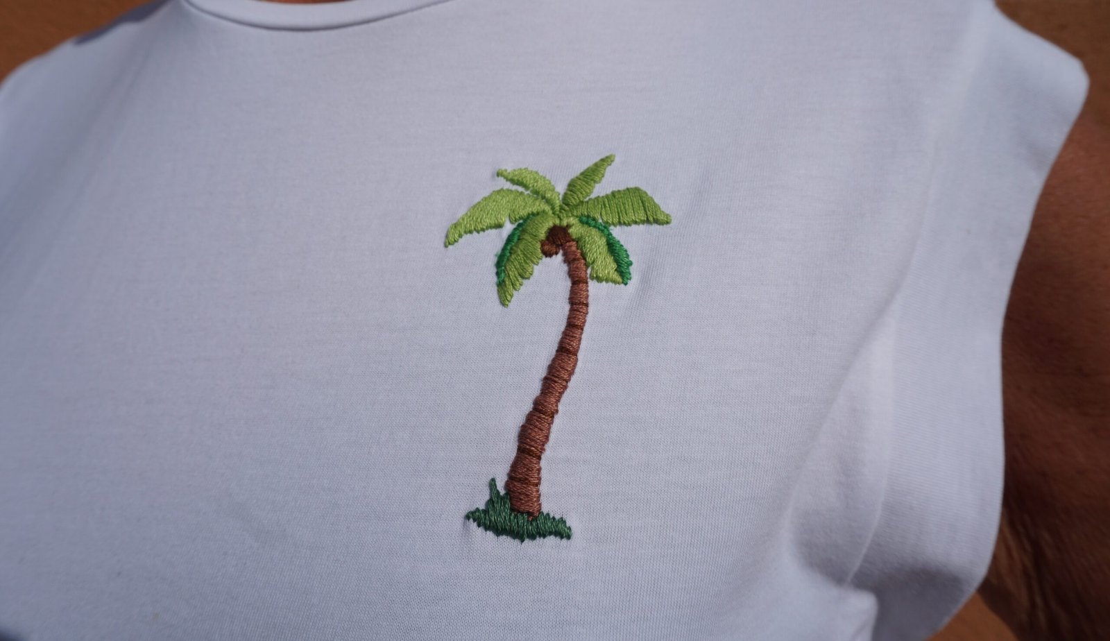 vue rapprochée d'un palmier brodé à la main sur un tee-shirt blanc