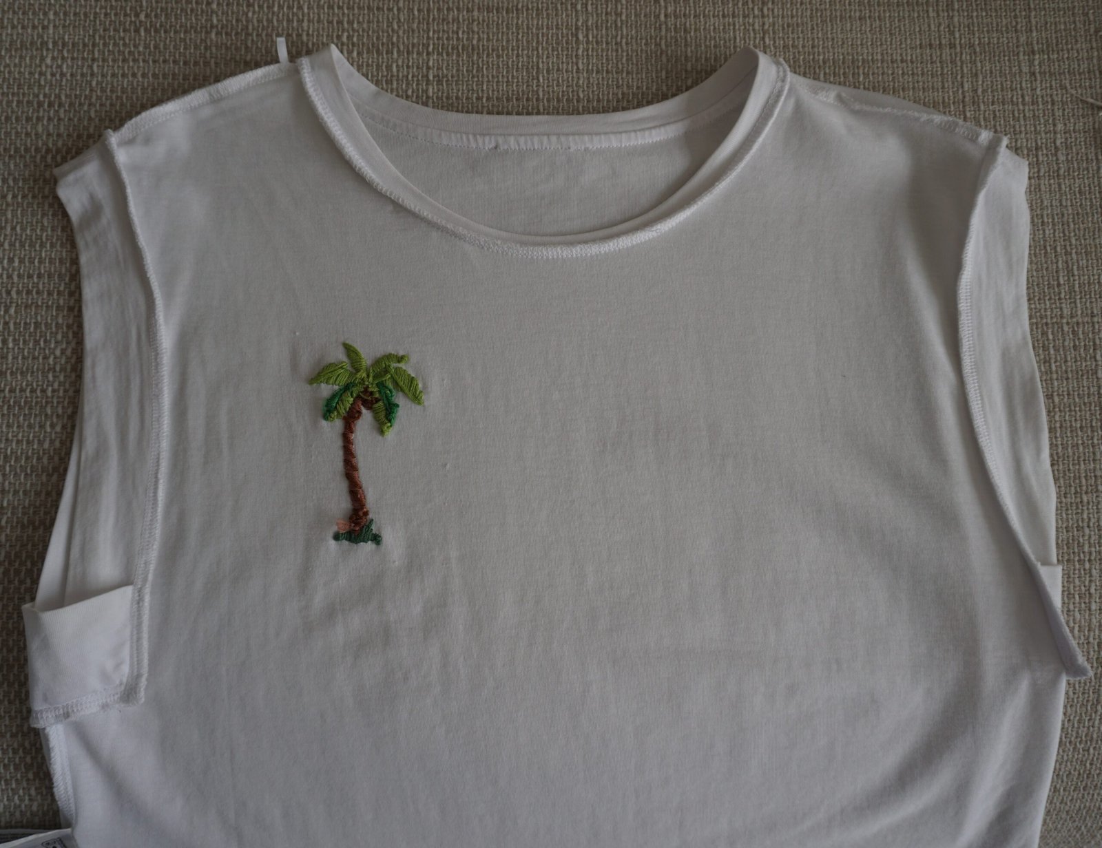 broderie à la main d'un palmier sur un tee-shirt blanc à plat