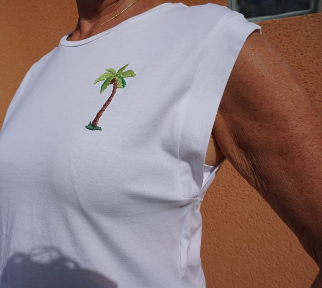 broderie à la main d'un palmier sur la poitrine d'un tee-shirt blanc porté, vu de face
