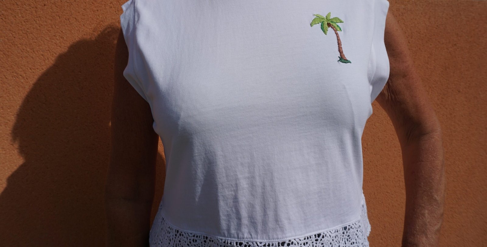broderie à la main d'un palmier sur la poitrine d'un tee-shirt blanc porté, vue large