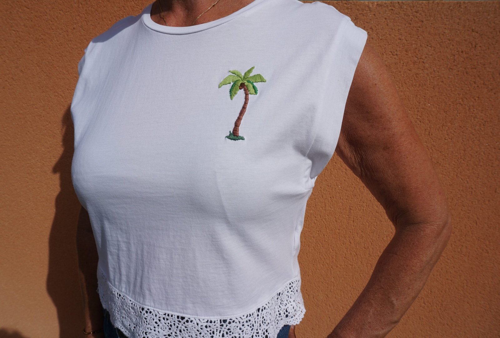 broderie à la main d'un palmier sur la poitrine d'un tee-shirt blanc porté, vu de trois quarts