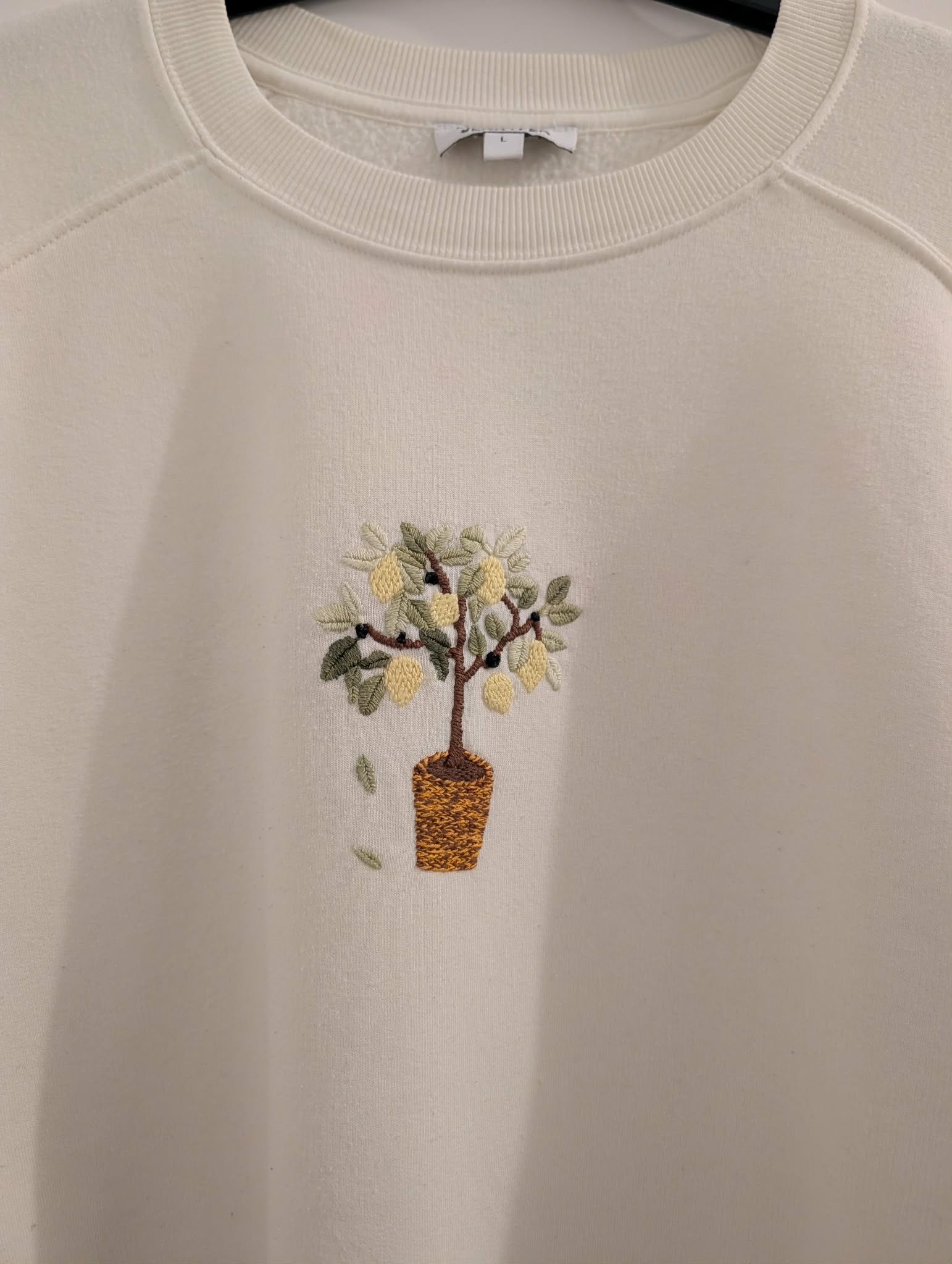 broderie à la main d'un citronnier en pot sur la poitrine d'un sweat écru